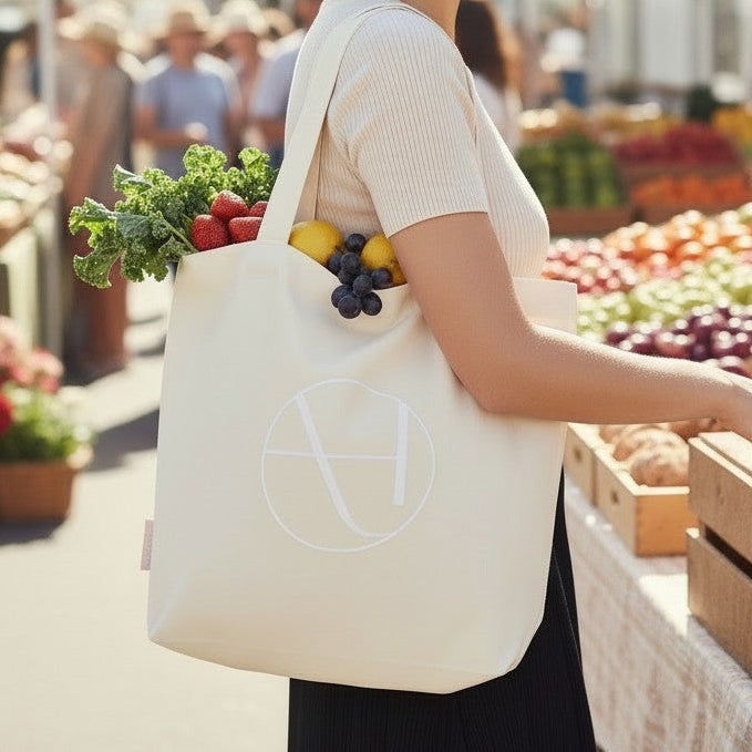 Woman shopping at an outdoor farmers market with a reusable bag.