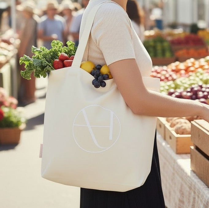 Woman shopping at an outdoor farmers market with a reusable bag.